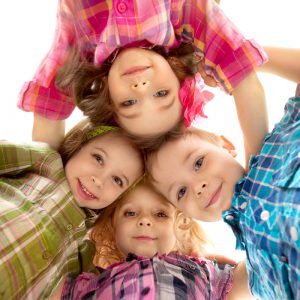 Smiling kids in a huddle, all wearing plaid shirts